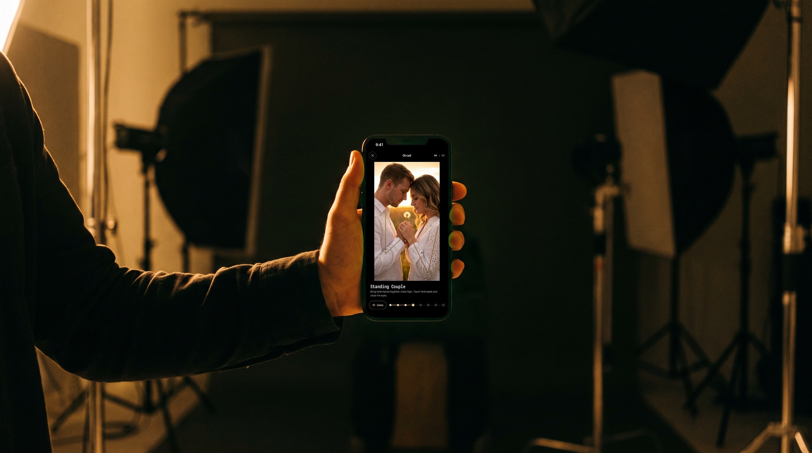 On set on an iPhone held up in a photo studio, a couple pose shown full screen on true black